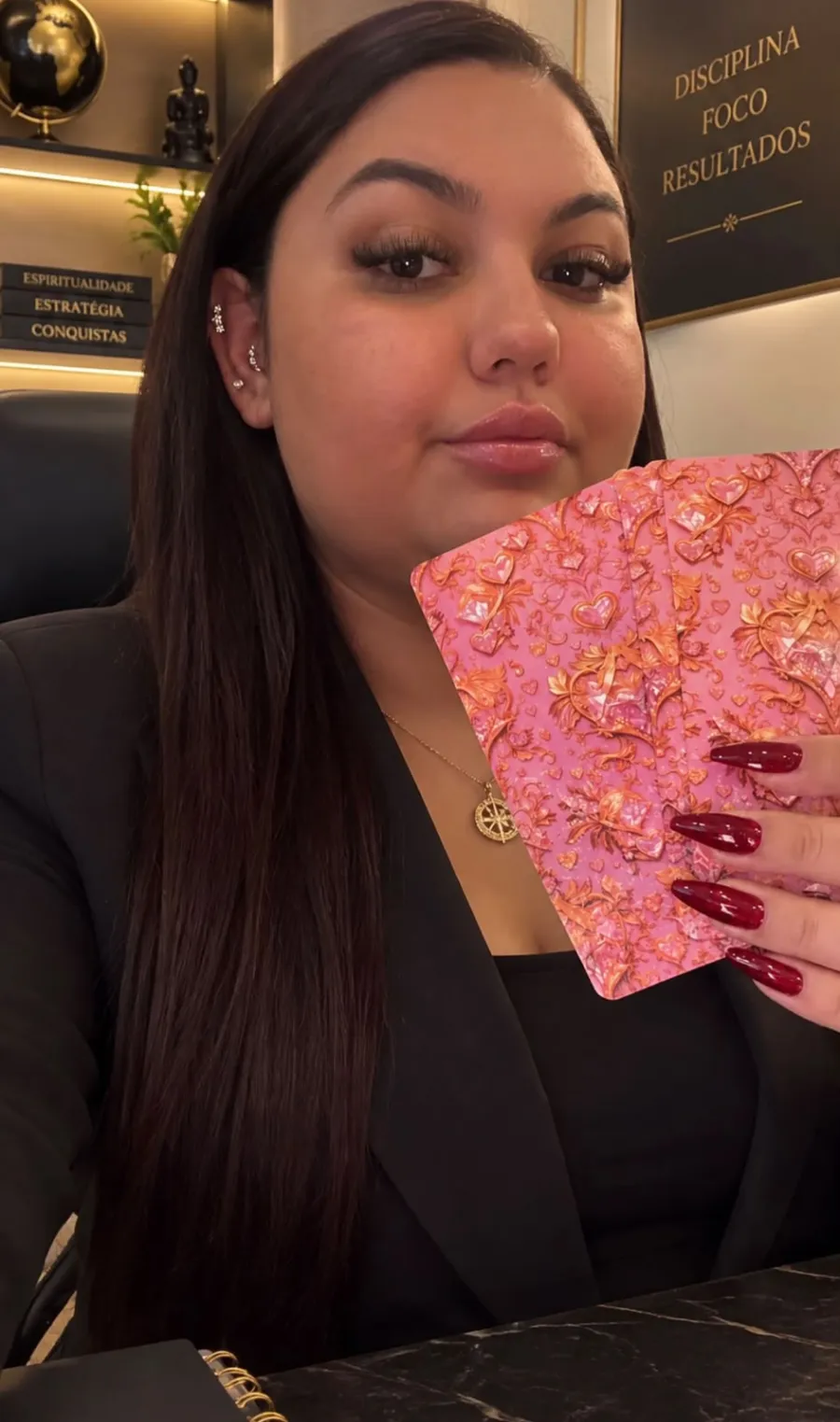 Alice mostrando baralho de cartas rosa ornamentado, com unhas vermelhas